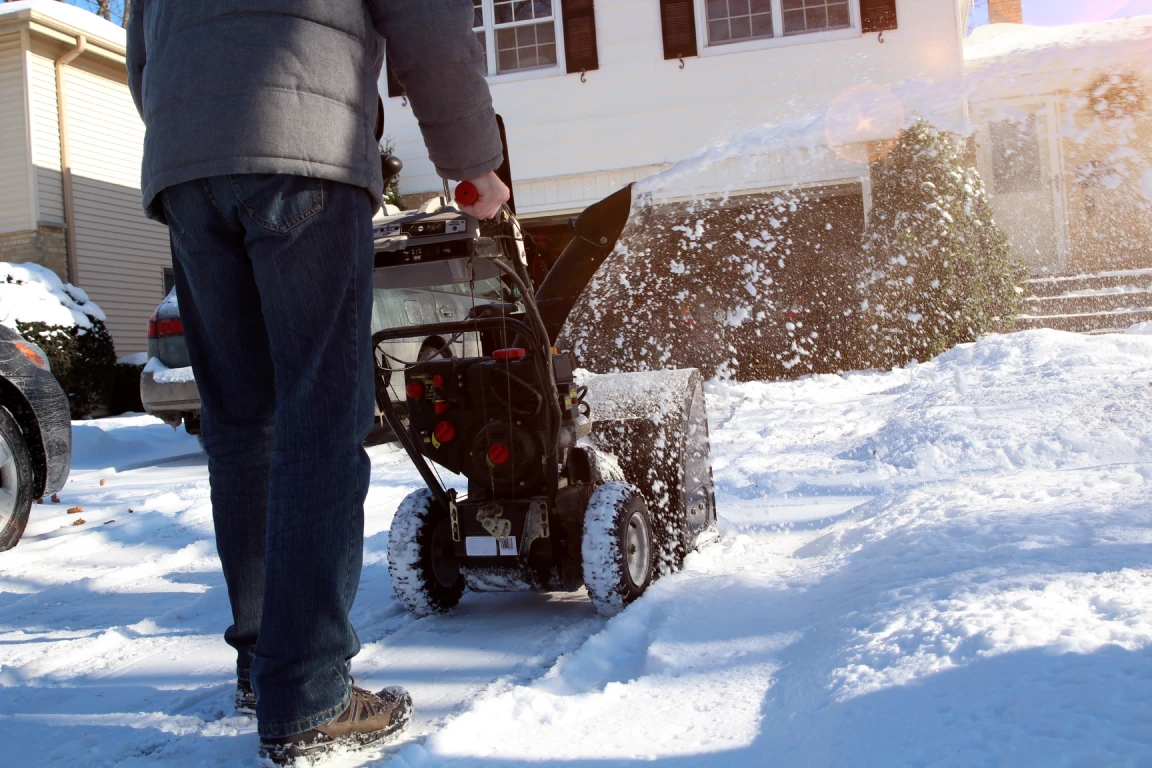 Homeowner snow blowing driveway at Massachusetts home