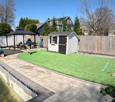 Artificial turf installation Massachusetts backyard pool paver patio crew working