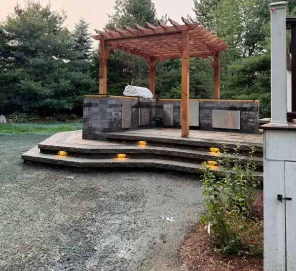 Outdoor kitchen pergola stone steps LED lighting Winchester MA evening hardscape installation