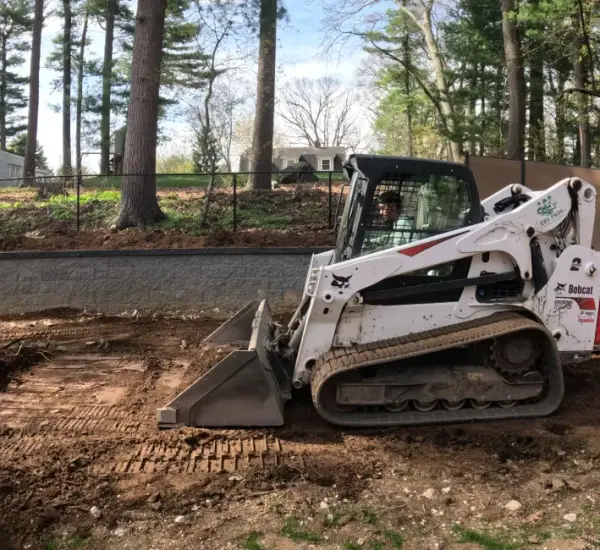 Bobcat skid steer preparing foundation for paver patio installation in Lexington Massachusetts