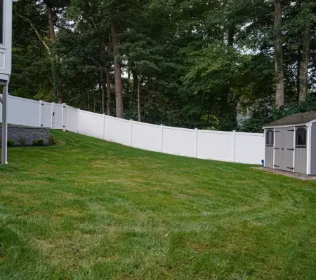 Professional sod installation Massachusetts sloped yard white vinyl fence shed