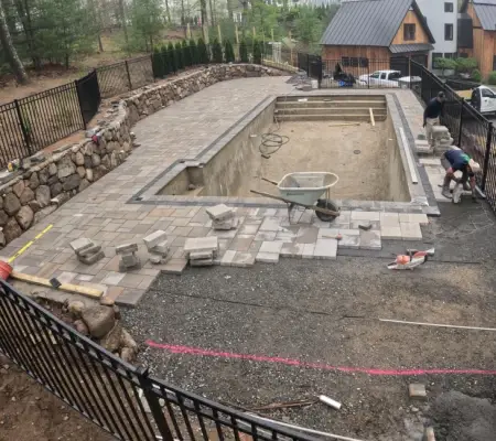 Stone wall and paver deck mid-construction, MA pool build